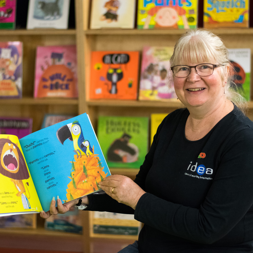 member of staff reading children's book