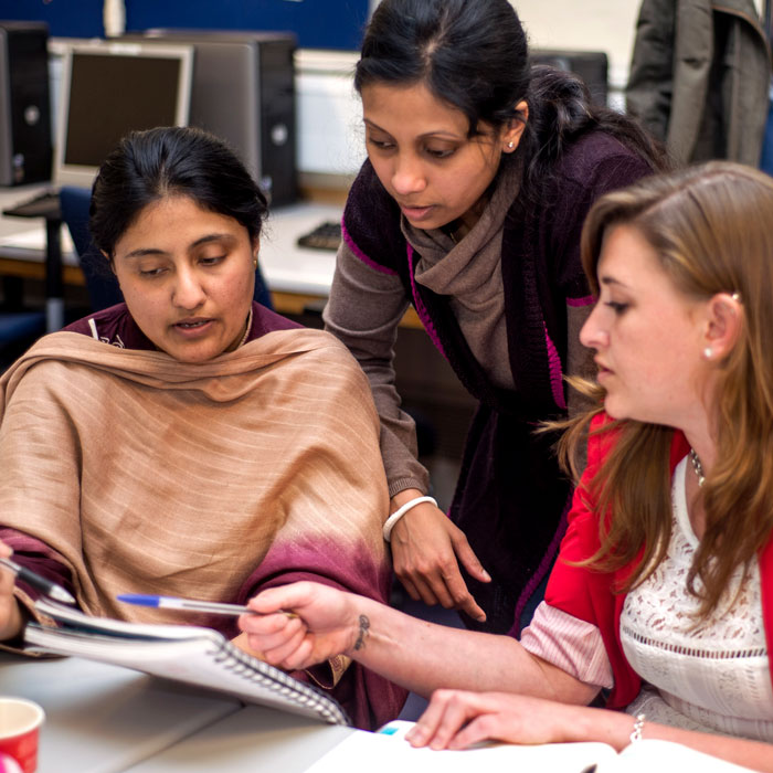 three learners looking at a workbook